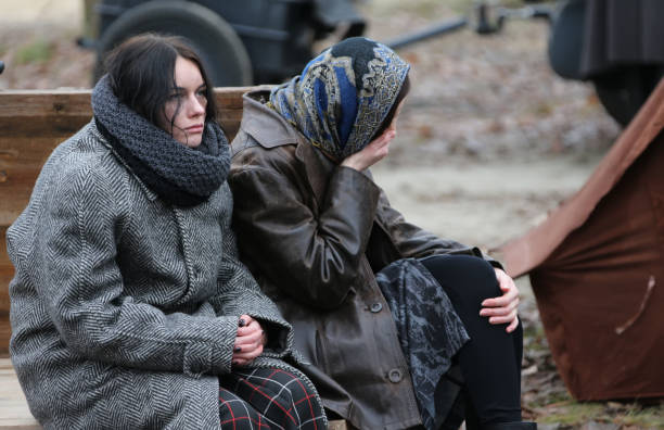las mujeres cansadas están sentadas en el frío. refugiados. refugiados - helado condición fotos fotografías e imágenes de stock