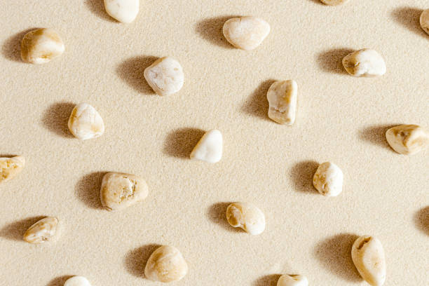 istock Pattern with close up pebble sea stones on sand texture. Layout from natural stone neutral natural tones. Minimal style sandy background 1352476229