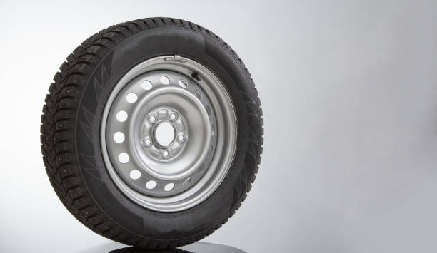 istock Car wheel and winter studded tire on grey background 1352476824
