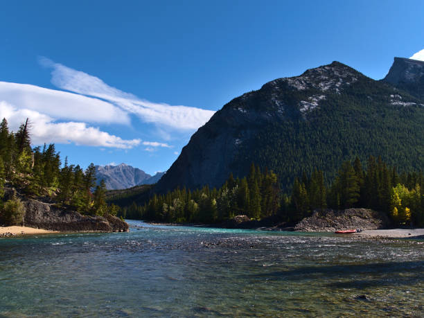 tranquil scene with flowing bow river near banff, banff national park, canada in the rocky mountains on sunny day in autumn with rafting boat on the shore and mount rundle. - rafting beauty in nature blue canada imagens e fotografias de stock