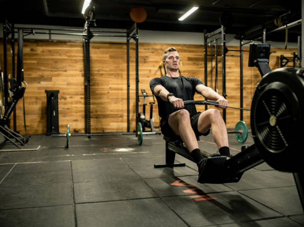 istock Young man exercising on rowing machine in the Gym 1352480605