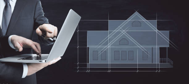 istock Businessmen using laptop with abstract drawing of creative house project blueprint on black background. Construction, teamwork, architecture, designer and plan concept. 1352481200