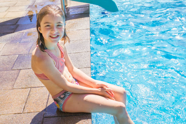 istock child girl having fun in Pool on the summer time sit on side 1352481379