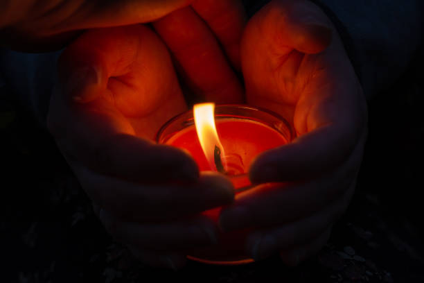 istock A red burning candle between a woman's palms. The woman shelters 1352483417