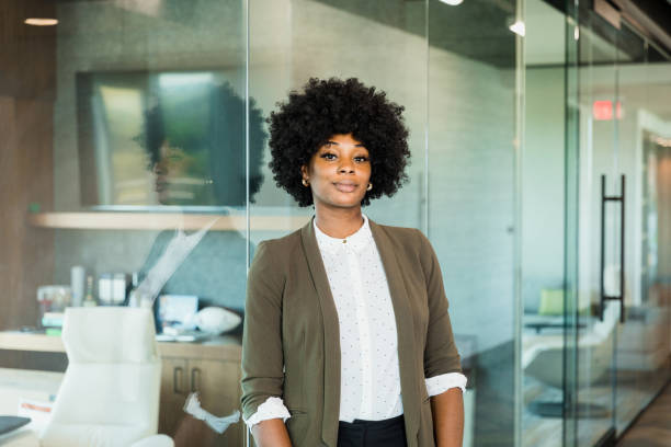 Confident female lawyer stands outside office The confident, mid adult female lawyer leans against the glass wall of her office. natural hair stock pictures, royalty-free photos & images