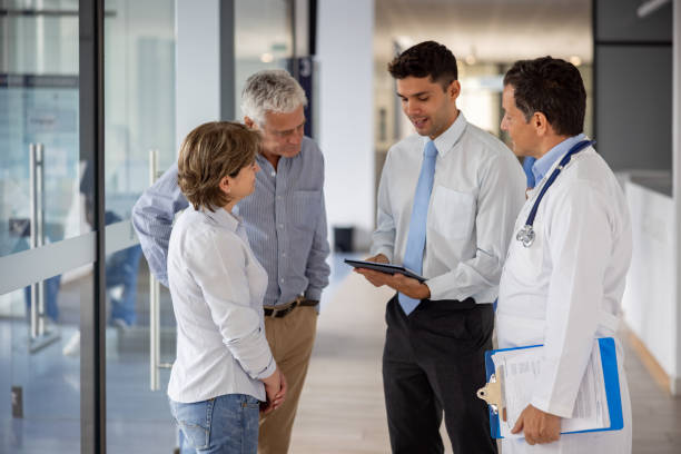 Patients talking to the hospital manager about their health insurance coverage Latin American patients talking to the hospital manager and a doctor about their health insurance coverage medical insurance stock pictures, royalty-free photos & images
