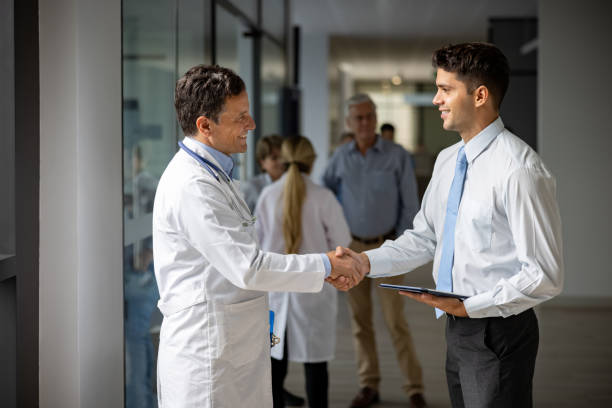 un représentant des ventes médicales salue un médecin avec une poignée de main à l’hôpital - industrie pharmaceutique photos et images de collection