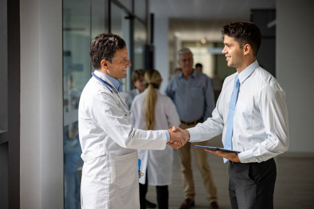 Medical sales representative greeting a doctor with a handshake at the hospital Latin American medical sales representative greeting a doctor with a handshake at the hospital while presenting some medicines - pharmaceutical industry concepts pharmaceutical industry stock pictures, royalty-free photos & images