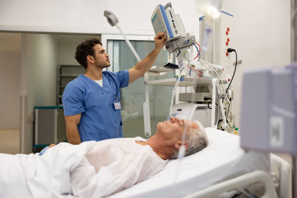 Nurse at the hospital checking the vitals on a hospitalized patient Latin American nurse at the hospital checking the vitals on a hospitalized patient - healthcare and medicine concepts. **DESIGN ON MONITOR BELONGS TO US** intensive care unit stock pictures, royalty-free photos & images