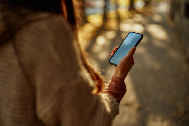 istock Unrecognizable woman using phone outdoors 1352491363