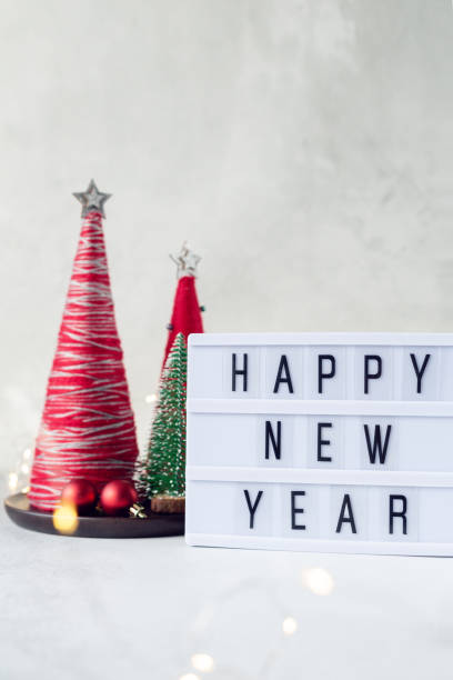 istock Lightbox with text HAPPY NEW YEAR with yarn wrapped XMAS cone trees. New year celebration. Soft focus, bokeh effect 1352492281