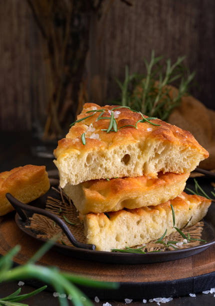 Focaccia típica do Mediterrâneo com azeite e alecrim em um fundo escuro - foto de acervo