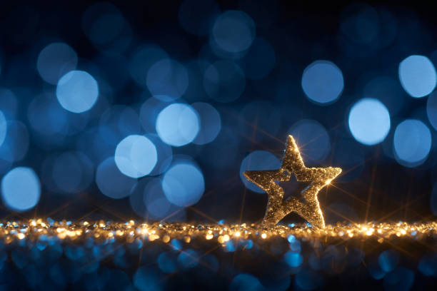 Funky Blue Christmas Star - Background Defocused Gold Bokeh Still life photography of an abstract Christmas background. Moravian glitter star on golden shiny glitter, lens flares, and defocused blue lights. Native image size: 7952x5304 christmas star shape christmas lights blue stock pictures, royalty-free photos & images