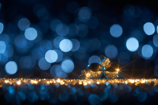 Funky Blue Christmas ornaments - Background Star Defocused Gold Bokeh Still life photography of an abstract Christmas background. Christmas tree baubles on golden shiny glitter, lens flares, and defocused blue lights. Native image size: 7952x5304 christmas star shape christmas lights blue stock pictures, royalty-free photos & images