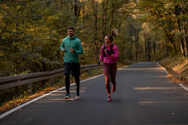 istock Mid aged couple running in the forest road 1352496428