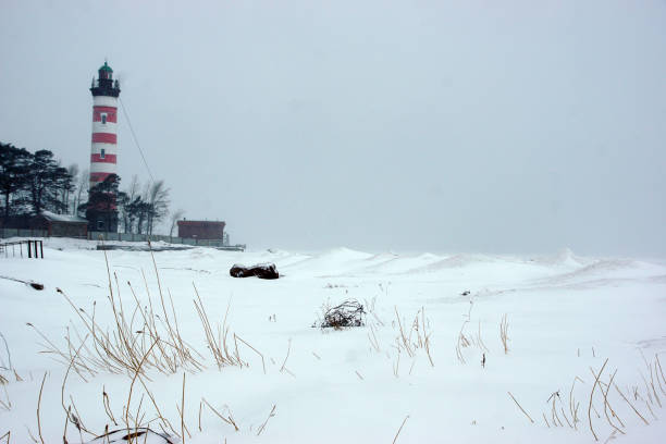 istock Lighthouse on the bay with red stripes, poor visibility due to snowfall 1352497112