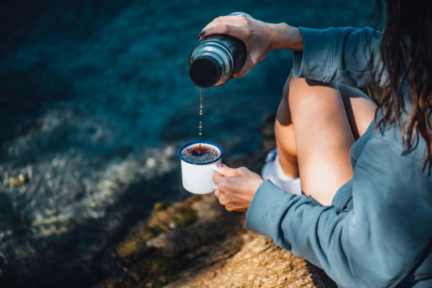 istock Woman Drinking Coffee From Her Thermos on the Beach 1352498029