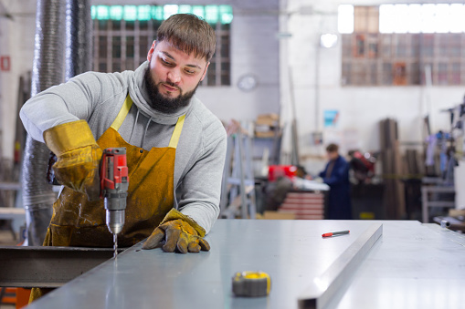 Portrait of  man  engineer drilling metal sheet  in workshop