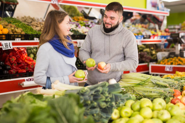 istock Glad couple choosing vegetables in grocery shop 1352498764