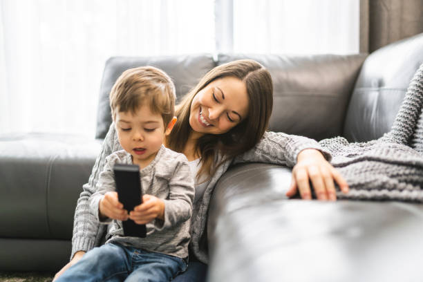 istock Mother and her son are watching tv while sitting on a couch 1352499348