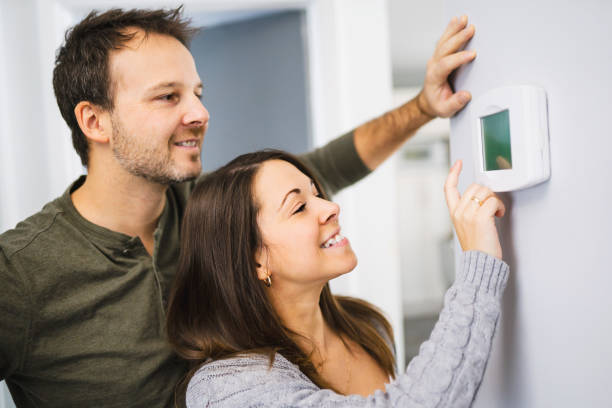 Nice couple set the thermostat at home stock photo