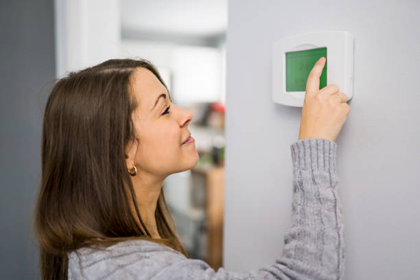 Woman set the thermostat at house. stock photo