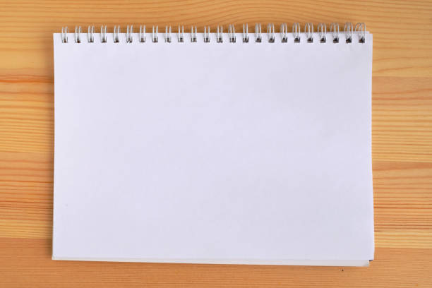istock horizontal blank copybook with metallic white spiral on a wooden background. Blank notepad mockup 1352499919