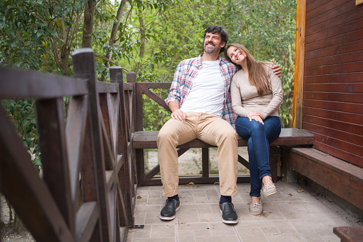 A happy couple in love is sitting on a bench at a wilderness resort cabin