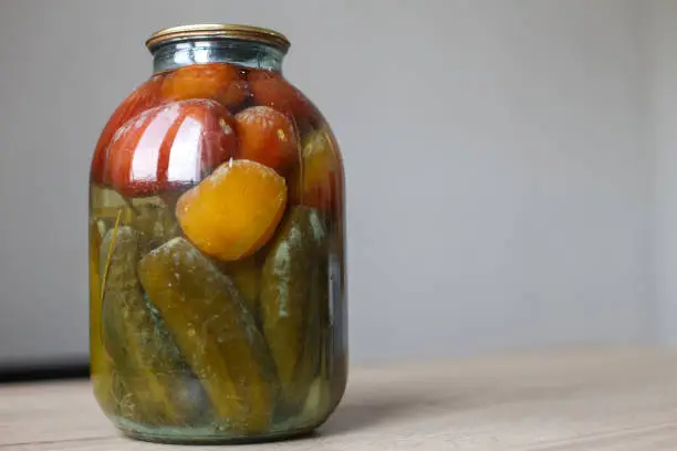 spoiled can of vegetable seaming. Glass jar with homemade pickled tomatos and cucumbers with white fungus and mold