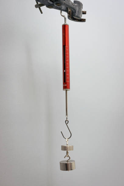 Weights hang from a dynamometer to measure force Dynamometer with weights to measure force (in grams). Science experiment, used in physics class. dynamometer stock pictures, royalty-free photos & images