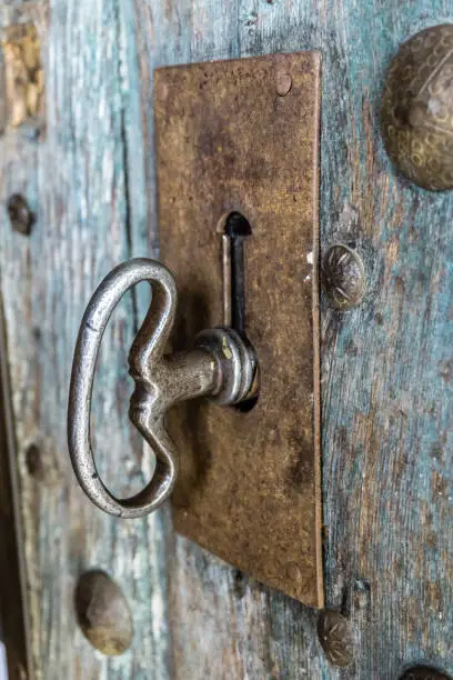 Photo of Close-up view of a key in the lock of an antique wooden door.