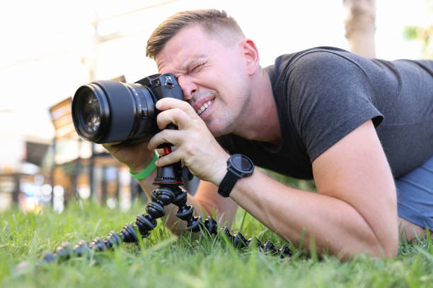 istock Male photographer makes photos on tripod while lying on ground 1352506432