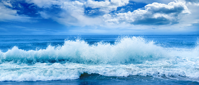 Bright ocean panoramic landscape in blue tones. Sea waves and beautiful sky with white clouds.