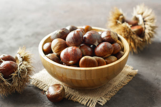 istock Fresh raw chestnuts on rustic table, Chestnut with thorny branch 1352506858