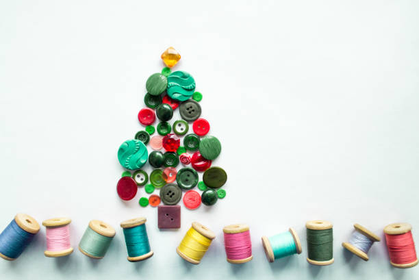 istock A Christmas tree made of buttons green, red color. Multicolored threads with wooden spools. White background, copy space. Creative Christmas concept 1352508664
