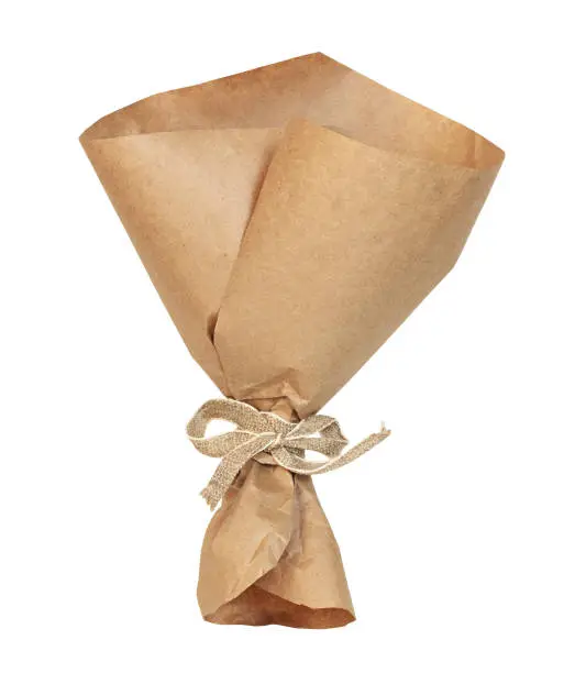 Photo of Empty craft paper wrapping cornet tied with beige canvas ribbon isolated