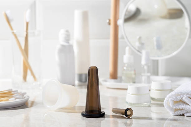 Vacuum jar for massage in the bathroom. Vacuum jar for massage in the bathroom. Mirror, massage oil, towel, cream, cotton swabs in the background. cupping therapy stock pictures, royalty-free photos & images