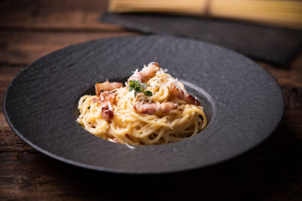 istock Pasta Carbonara in dark plate on a white wooden table 1352514788