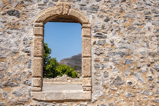 Window frame with arch on a stone wall at Venetian Castle Fortezza at Chora Kythira island, Greece. View from an opening of Kythera Kithira monument.