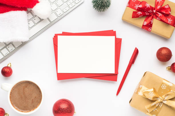 photo de dessus de la tasse de clavier de boire chaud père noël chapeau pin jouet rouge balles d’arbre de noël boîtes cadeaux pile d’enveloppes rouges feuille de papier et stylo sur fond blanc isolé avec copyspace - paper stack cup index card photos et images de collection