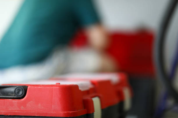 A male carpenter sits at home next to a red toolbox. Close up of plastic container with tools