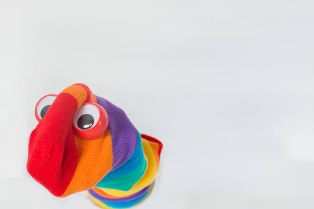 istock Cute sock puppet with rainbow flag sock and plastic red eyes. White background, copy space. Fighting for LGBTQ+ rights. 1352516894