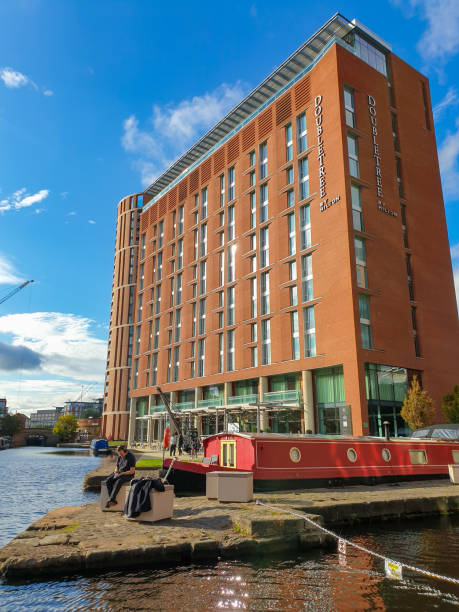 un uomo siede lungo il fiume vicino all'ingresso di granary wharf sul fiume aire. - leeds england yorkshire canal museum foto e immagini stock