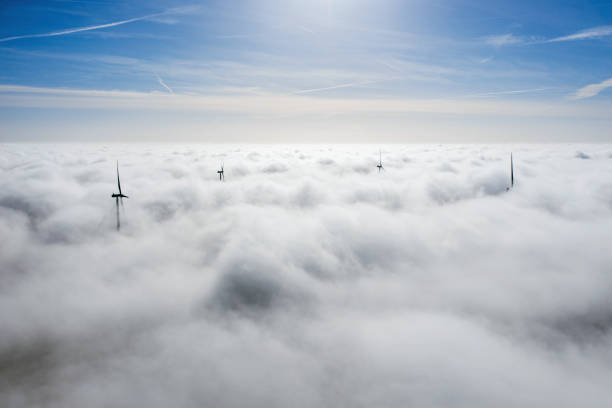 ветропарки, торчащие над облаками, вид с воздуха на дальние пропеллеры турбин - fog wind power energy fuel and power generation стоковые фото и изображения