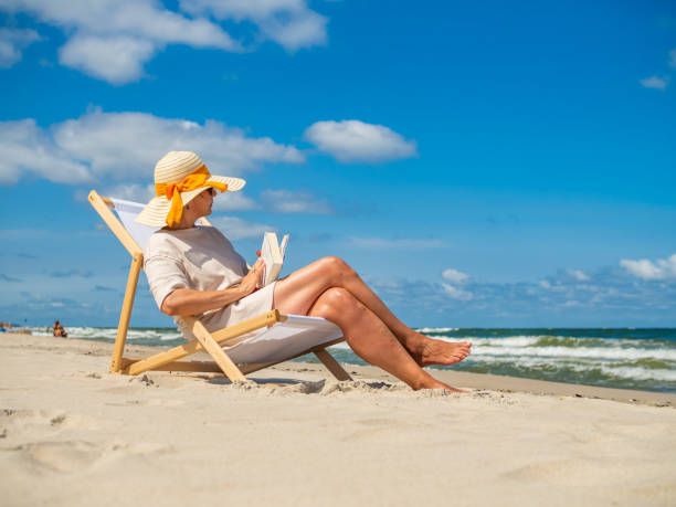 istock Woman relaxing on beach reading book 1352524751