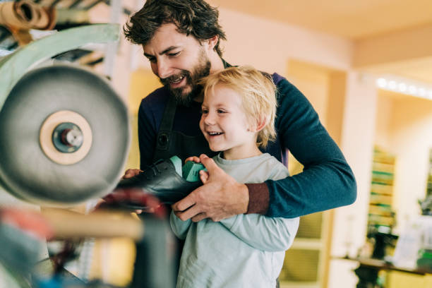 Shoemaker and his cute little boy in the workshop. Smiling father is teaching his son making a leather luxury shoes in the workshop. shoe mold stock pictures, royalty-free photos & images