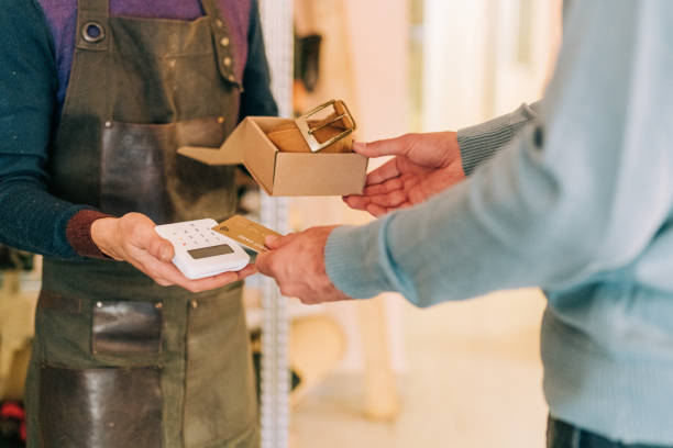 istock Man buying handmade leather belt from craftsperson and using credit card. 1352524795