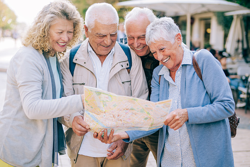 Shot of a group of elderly friends standing outdoors in the city looking at a map. Group of seniors using city map for finding their location.