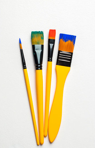 Set of paintbrushes with multi colored paints. White background.