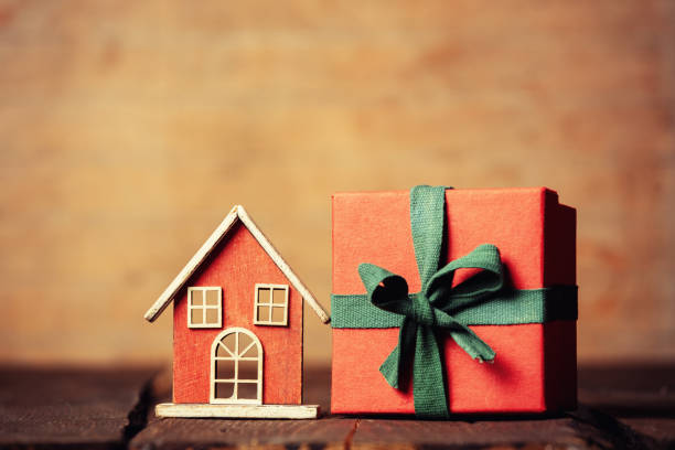 istock Little wooden house toy and gift box on a table 1352531410